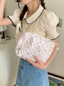 Pochette matelassée rose à motif d'ours, portée par un mannequin en décor de style