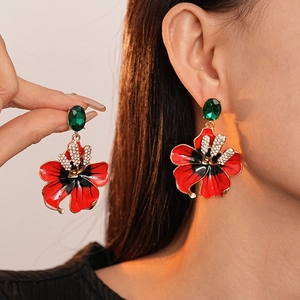 Boucles d'oreilles fleur rouge vintage avec pierres vertes et strass sur un mannequin