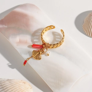 Detail of adjustable gold ring with hanging seashell, red bead and pearl charms