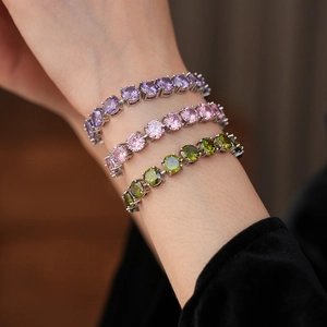 Detail of silver clasp bracelets with purple, pink, and olive green round cubic zirconia stones