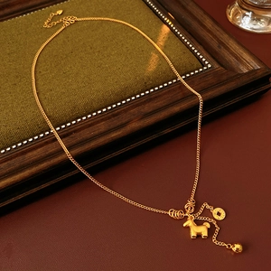 Detail of gold pony pendant necklace with coin charms on vintage green fabric background