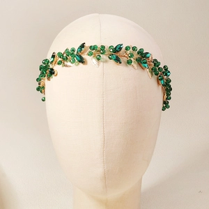 Detail of handmade gold bridal headband with green crystals and metal leaves