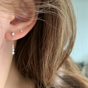 Close-up of minimalist silver drop earrings with cubic zirconia on model's ear