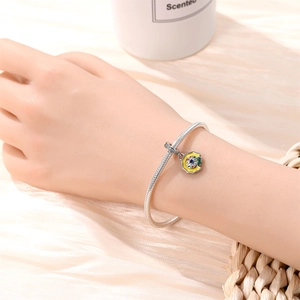 Detailed view of a silver charm bracelet with a colorful palette pendant on a wrist