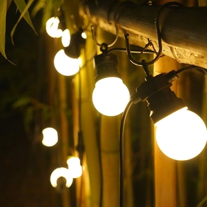 Close-up of waterproof G40 solar string lights hanging on bamboo in a warm garden setting