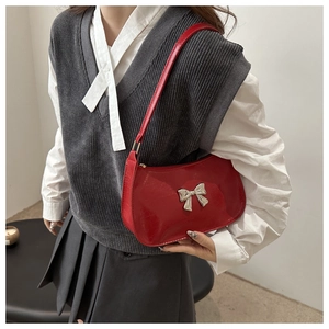 Detail of red glossy baguette bag featuring silver bow hardware and chic mirror finish