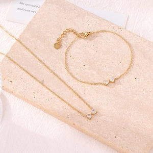 Ensemble collier et bracelet en acier doré avec pendentifs nœuds en zircons brillants