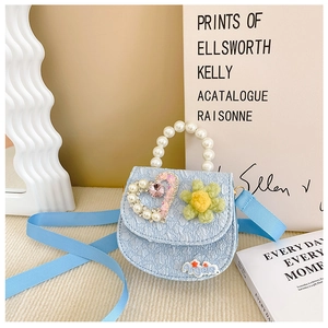 Detail of light blue girls' crossbody bag featuring pearl handle and heart-shaped jewel