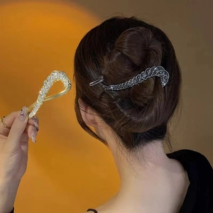 Close-up of twisted rhinestone hair clips in gold and gunmetal finish for elegant buns