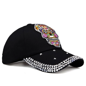 Detail of colorful sugar skull embroidery and silver rhinestones on black denim baseball cap