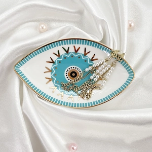 Detailed view of luxury drop earrings on an eye-shaped ceramic jewelry storage tray