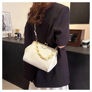 Beaded handle detail on white shell bag styled with a professional suit and white skirt
