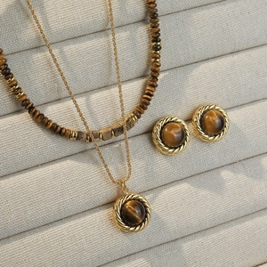 Tiger eye beaded necklace set with gold pendant and earrings on a jewelry tray