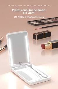 Detail of white portable LED makeup mirror showing built-in storage with comb and tweezers