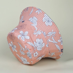 Detail of pink cotton bucket hat with white hand-drawn floral patterns and stitching