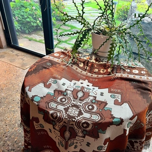 Detail of bohemian woven blanket with red geometric patterns and fringe edges on a table