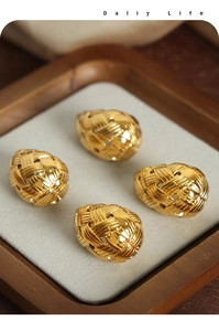 Macro detail of gold-plated egg-shaped jewelry beads with woven texture on wooden tray