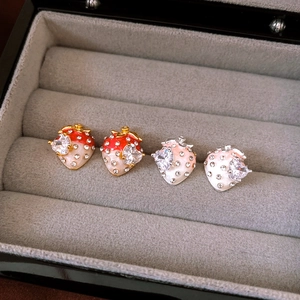 Vue détaillée de boucles d'oreilles fraises avec cristaux en cœur sur velours gris