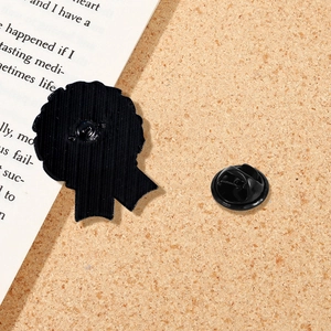 Custom black metal medal pin with serrated edges and clutch back on cork board