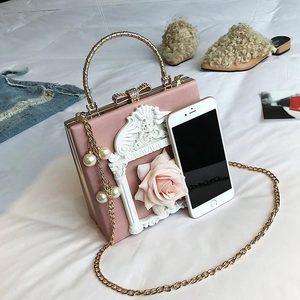 Pink floral box bag with architectural relief shown next to a phone for size reference