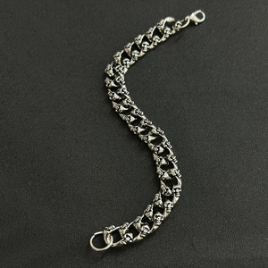 Detail of silver skull chain link bracelet with lobster clasp on dark background