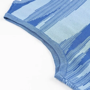 Gros plan détaillé de l'encolure côtelée et de la texture à rayures bleues de la robe en maille