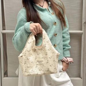 Floral canvas lunch tote bag with side pocket held by model in casual lifestyle setting