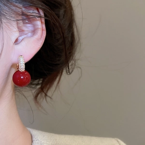 Close-up of red resin bead drop earrings with gold-plated zircon inlay on female model