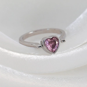 Detailed macro view of a silver ring with a sparkling pink heart-shaped zircon stone