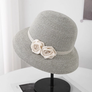 Détail d'un chapeau de paille gris avec élégantes roses en satin blanc et texture tissée