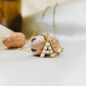 Detailed view of gold stainless steel necklace with pearl-inlaid letter A pendant