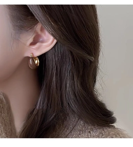 Close-up of teardrop brown tiger eye earring with gold trim worn by a model