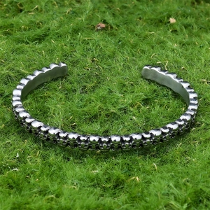 Detail shot of vintage punk skull carvings on an adjustable silver open cuff bracelet