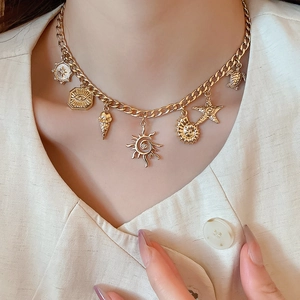 Detail of gold nautical charms necklace featuring starfish and sea shell on a female model