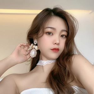 Elegant gold bow earrings with pearls and crystals shown on a model with lace choker