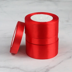 Close-up of vibrant red satin polyester ribbons in various widths on marble surface