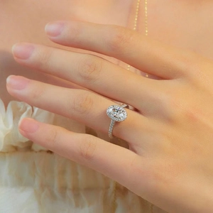 Close-up of elegant silver halo ring featuring a large oval stone on a female hand