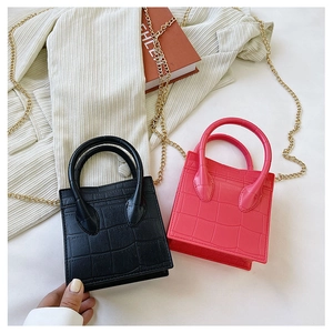 Detail of pink and black crocodile pattern mini bags with elegant gold chain straps