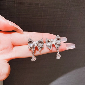 Elegant bow earrings with pearls and water drop pendant shown held by hand