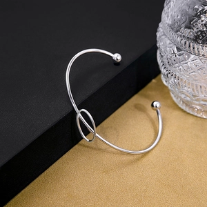 Detail of silver geometric open cuff bracelet with intertwined oval link and smooth beads