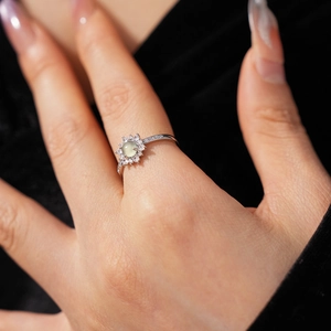 Close-up of a vintage sunburst ring with mint green stone worn on a finger