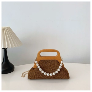 Detail of dark brown plush bag with a distinctive wooden handle and pearl chain decor