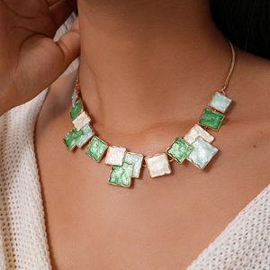 Close-up of geometric square necklace with green enamel panels and gold borders