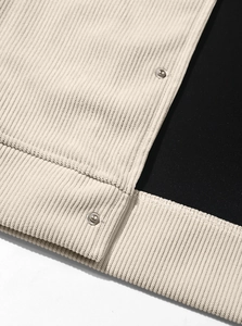 Close-up of beige corduroy jacket texture featuring metallic snap buttons and black lining