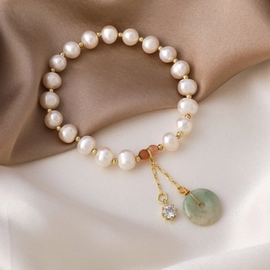 Detailed macro view of freshwater pearl bracelet with jade and rhinestone charms