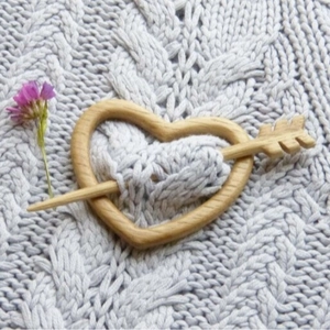 Handcrafted wooden heart brooch pin with arrow design on gray knit background