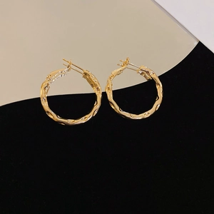 Macro shot of gold hoop earrings featuring irregular hammered texture and metallic luster
