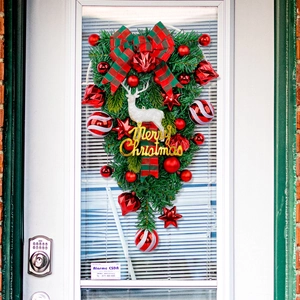 Christmas wreath with white reindeer, red baubles, and Merry Christmas sign on front door