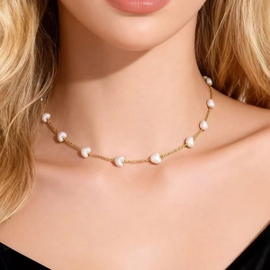 Primer plano de gargantilla elegante de acero dorado con perlas de corazón en modelo.