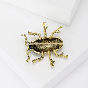 Golden beetle alloy brooch showing the textured metal back and secure pin clasp closure